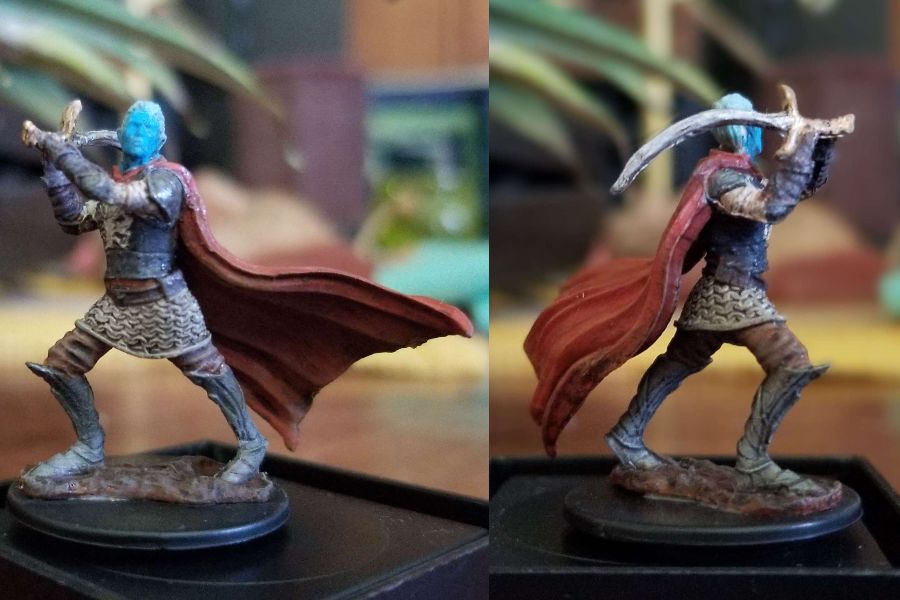 A blue skinned elf with white hair, silver armor and a red cape, swinging a sword.