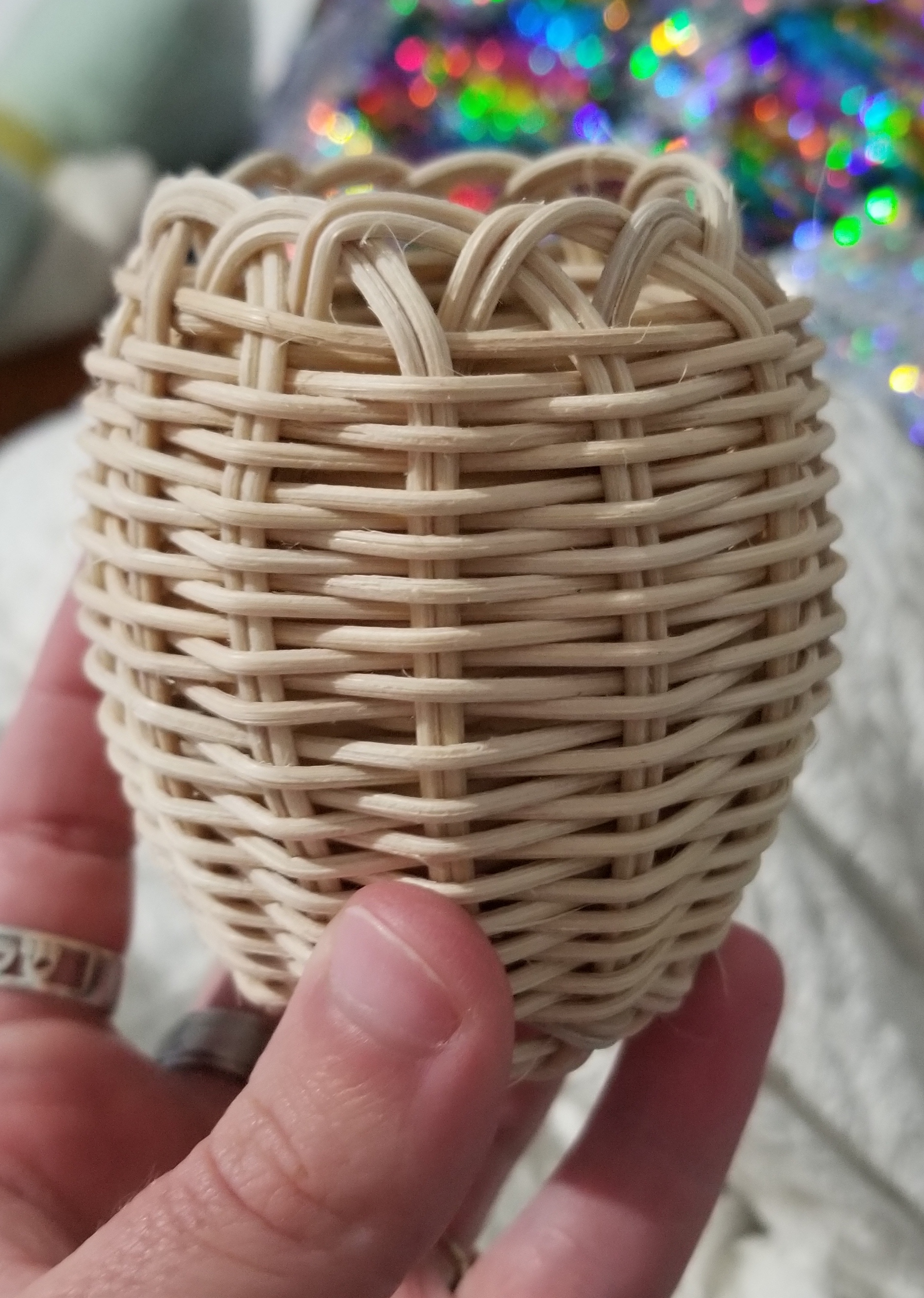 A small, oval-shaped, double-walled basket woven with natural reed.