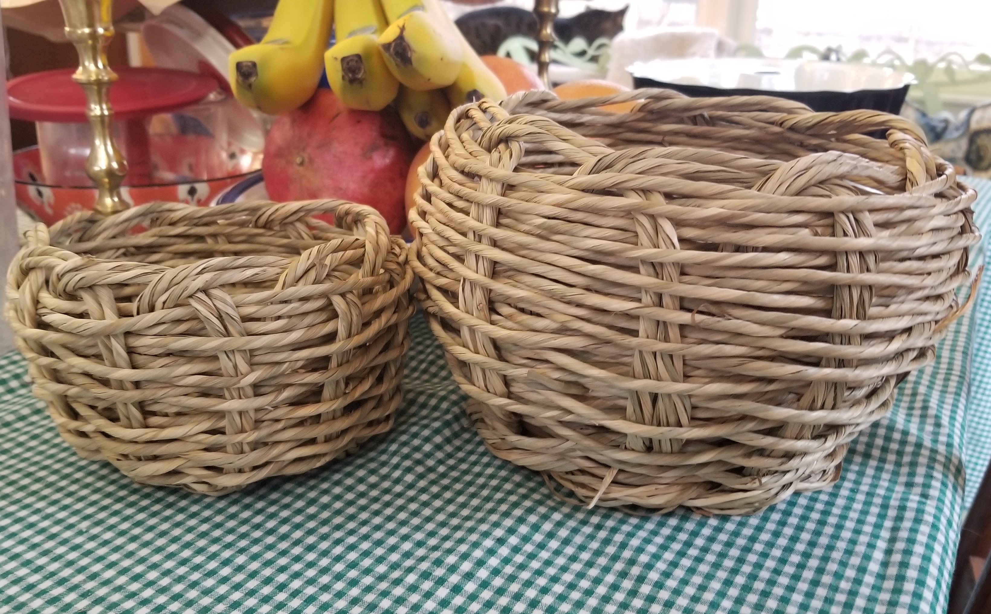 Two slightly lumpy handwoven twisted-seagrass baskets, one is small the other is a medium-large.